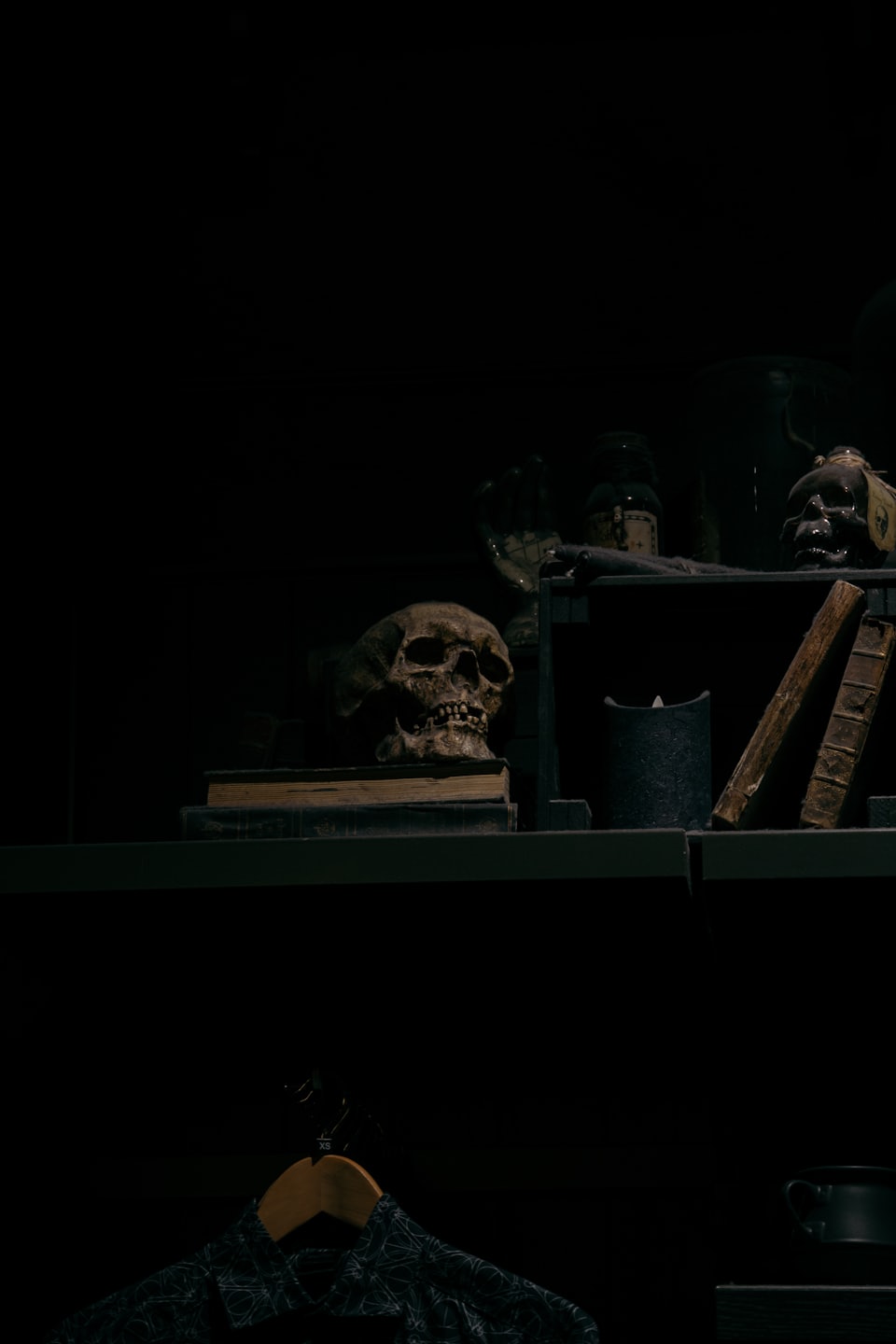 A weathered human skull rests on vintage leather-bound books.