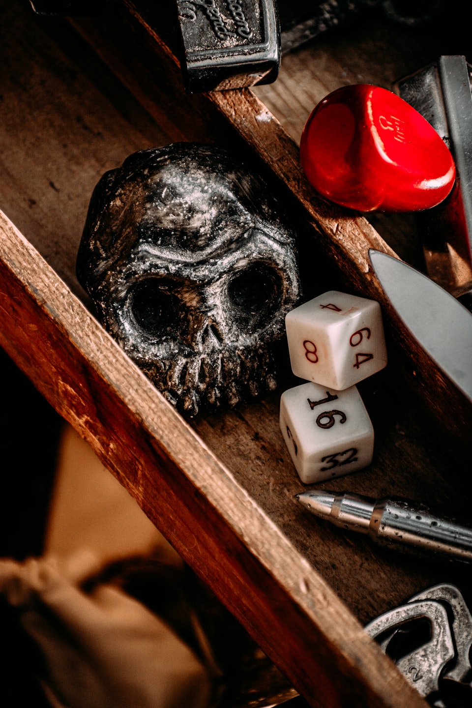 Skull, dice, heart, and tools arranged in a wooden tray.
