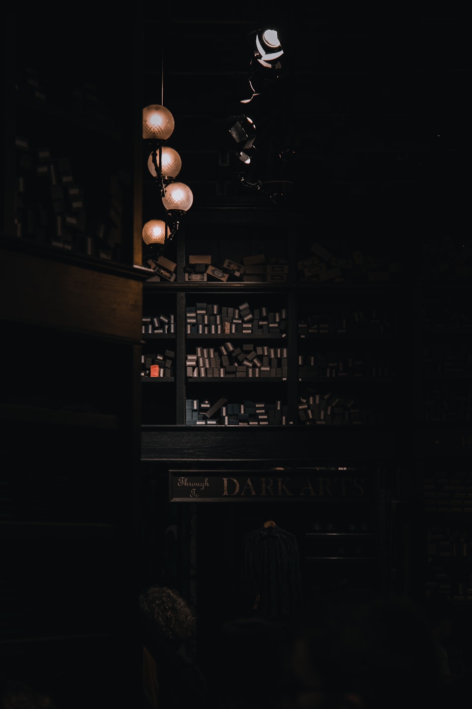 Wooden shelves hold many boxes above a Dark Arts sign.