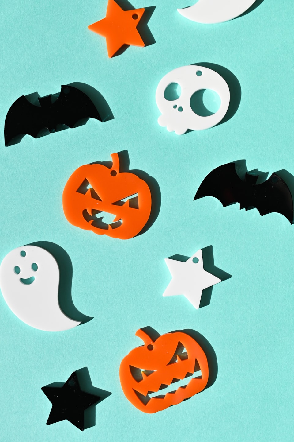 Halloween themed acrylic shapes scattered on a turquoise surface.