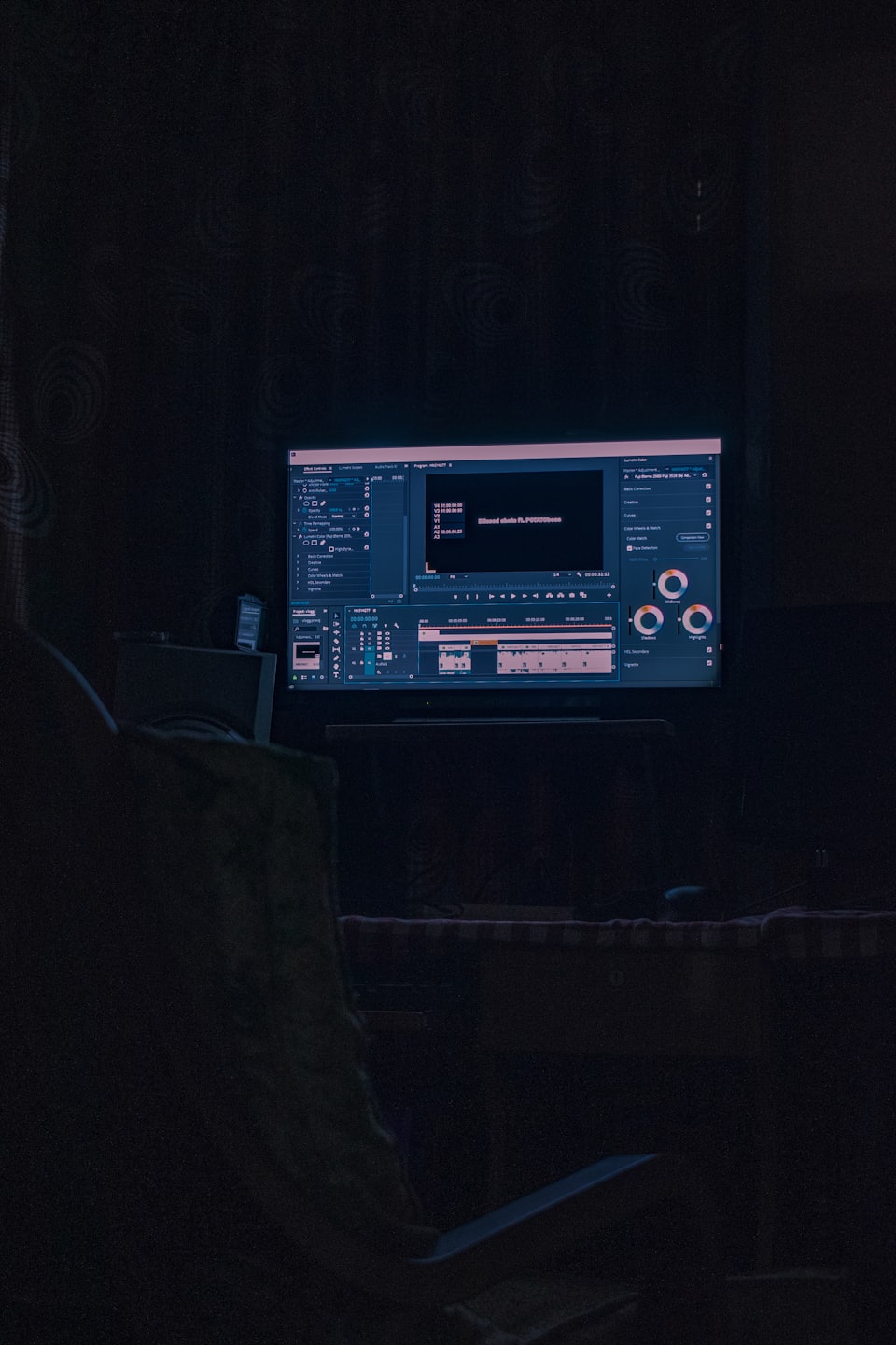Computer monitor displaying video editing software in a dark room.