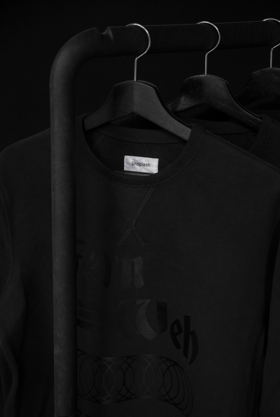 Black sweatshirt with white tag on clothing rack.